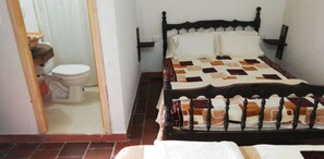 A bedroom with a bed, a wooden headboard, and a white toilet. - Posada Villa Alejo (Charta)