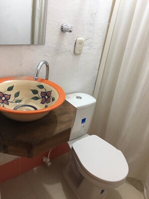 A bathroom with a ceramic sink, a toilet, and a shower curtain. - Posada Villa Alejo (Charta)