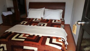 Uma cama com colcha estampada, cabeceira de madeira e almofadas brancas.