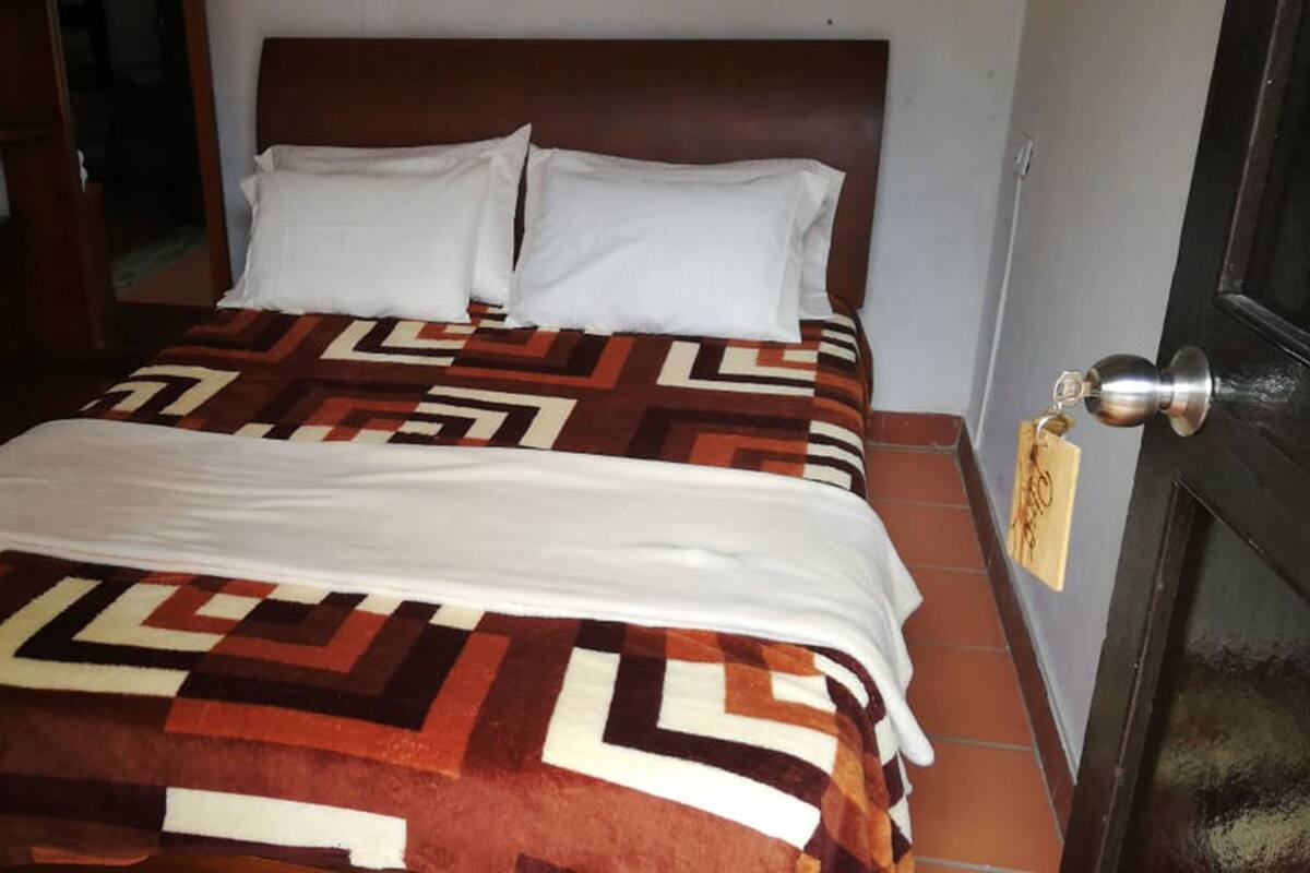 Ein Bett mit einem gemusterten Überwurf, einem hölzernen Kopfteil und weißen Kissen.
