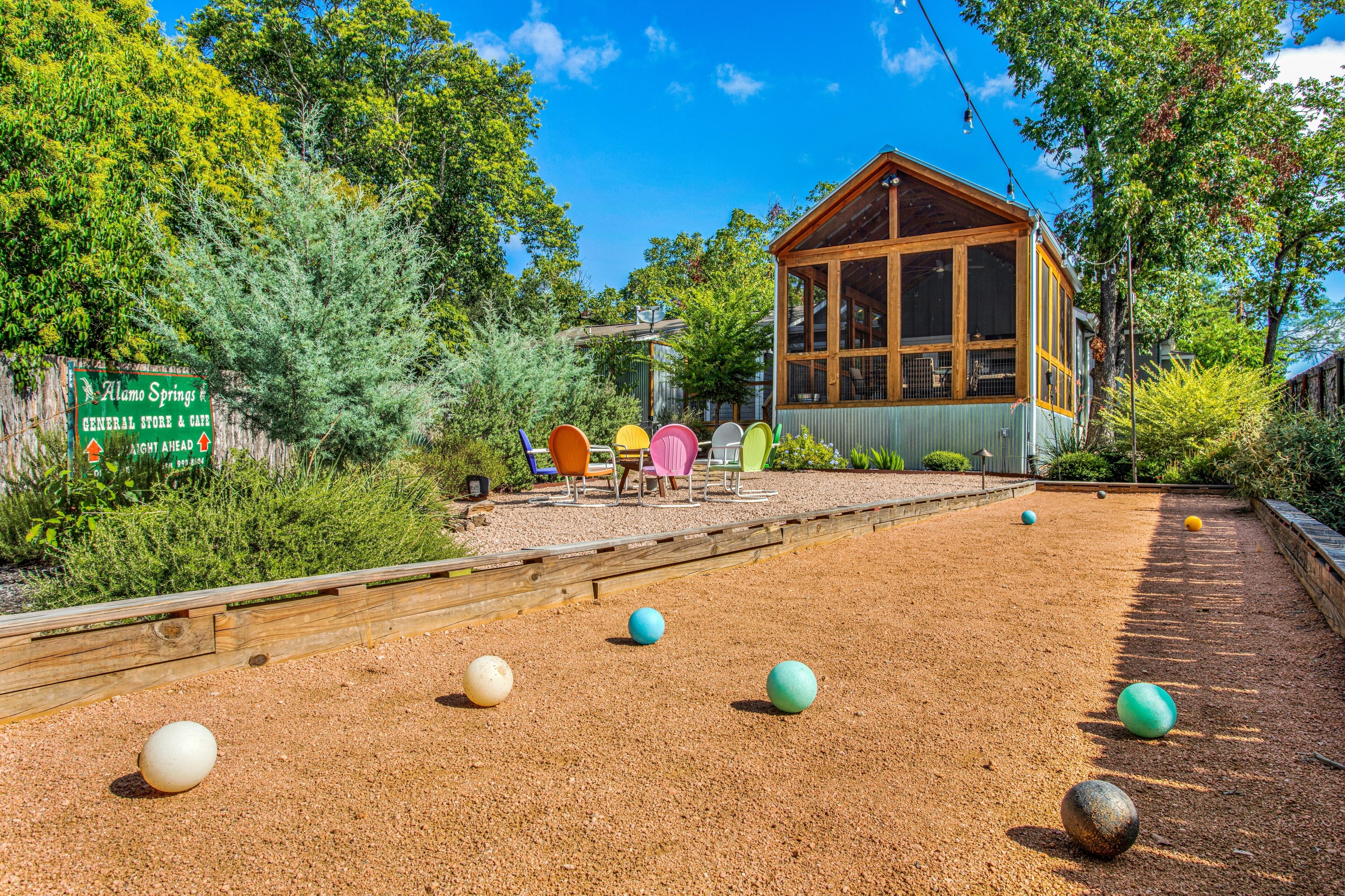 A courtyard with a bocce court, a wooden structure, and a sign for Alamo Springs General Store & Cafe.