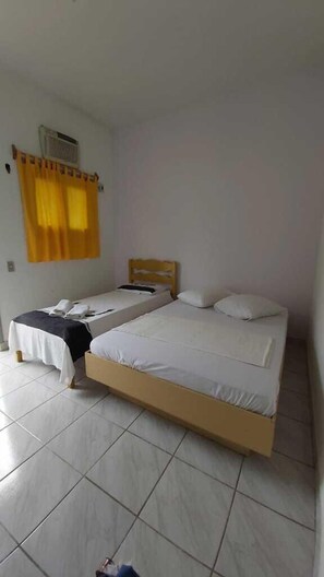 Una habitación con dos camas individuales, una mesita y un calentador fijado a la pared.