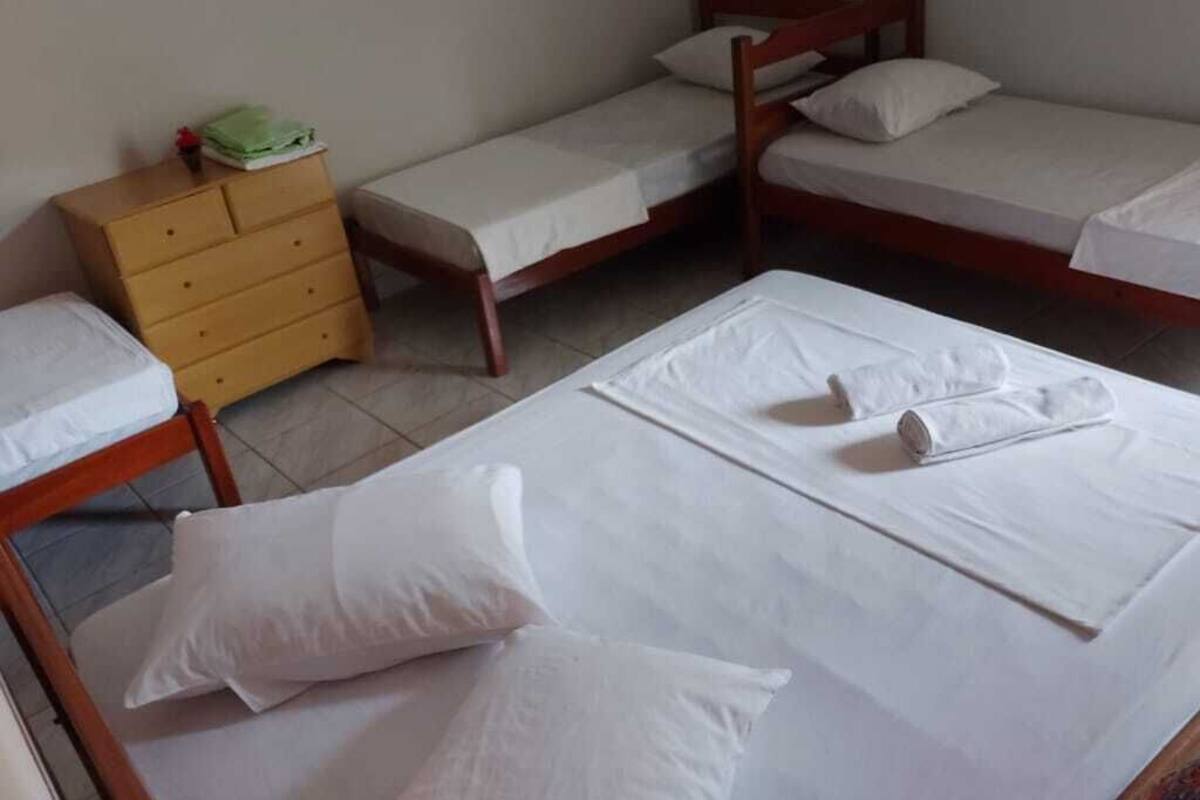Una habitación con dos camas de madera, un aparador de madera y piso de baldosas.