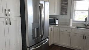 Una cucina moderna con elettrodomestici in acciaio inossidabile, mobili bianchi e pavimento in legno.