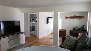 Un soggiorno con televisore, un divano e una decorazione a forma di pesce sul muro.