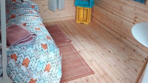 A cozy cabin room with a bed, a painting, and a small table. - The pines 4  x private chalets (Cheviot)