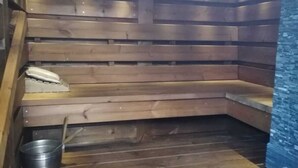 En sauna med træbænke og en stenvæg.