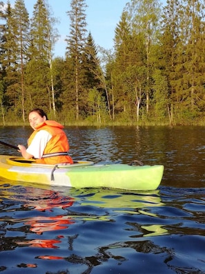 Henkilö kajakissa vesistöllä, jonka ympärillä on puita.