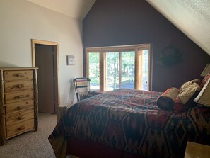 A bedroom with a bed, a wooden dresser, a chair, and a window with blinds. - Cozy home in heart of Sunriver w/ hot tub, close to Mt Bachelor (Sunriver)