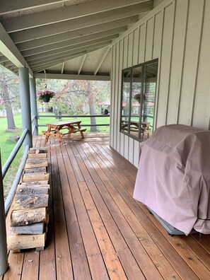 A covered porch with a wooden deck, a picnic table, and a barbecue grill. - Cozy home in heart of Sunriver w/ hot tub, close to Mt Bachelor (Sunriver)