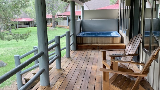 A covered porch with wooden flooring, a hot tub, and wooden chairs. - Cozy home in heart of Sunriver w/ hot tub, close to Mt Bachelor (Sunriver)