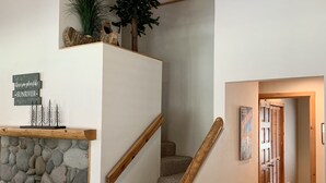 A staircase with a stone wall, wooden handrail, and a small Christmas tree. - Cozy home in heart of Sunriver w/ hot tub, close to Mt Bachelor (Sunriver)