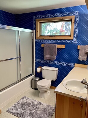 Ein Badezimmer mit Toilette, Waschbecken, Dusche und einem Fenster.