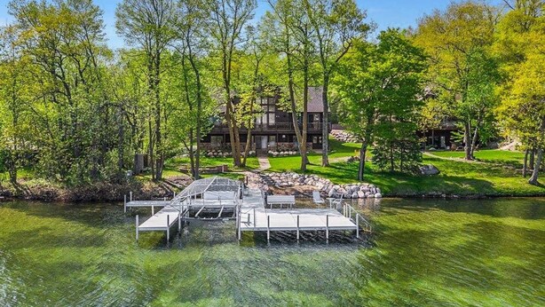 A lakeside property with a dock, a large house, and a well-maintained lawn. - Luxurious Expansive Cabin Escape on Gull Lake! (Nisswa)