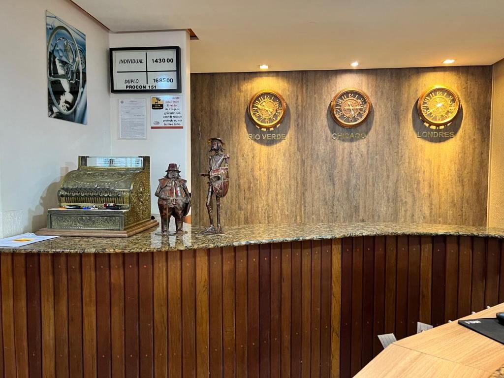 A reception desk with a wooden finish, a vintage cash register, and a statue of a man.