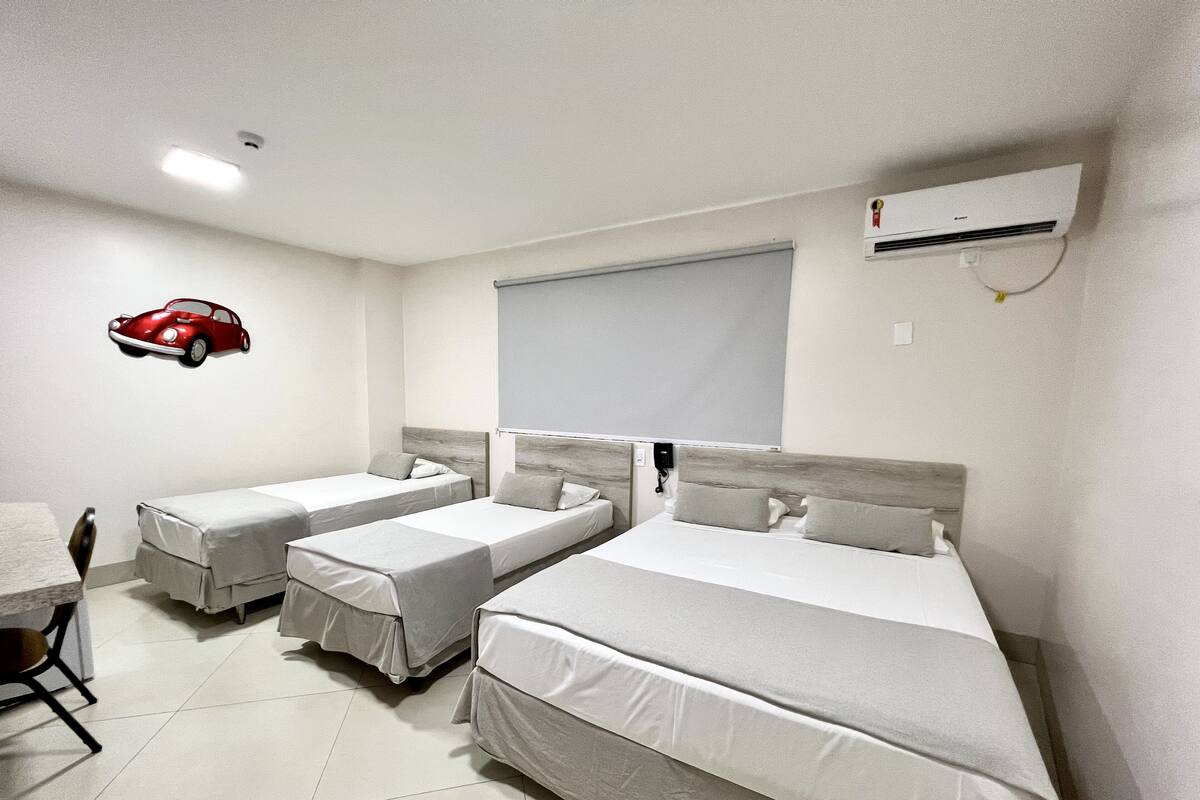 A hotel room with two single beds, a desk, and a chair.
