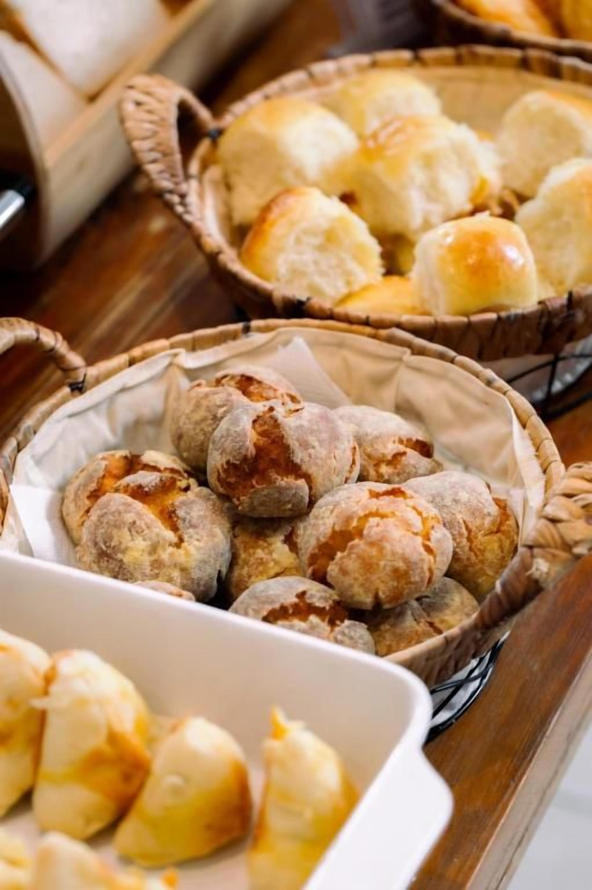 A variety of baked goods, including bread rolls and pastries, displayed in baskets and a white dish.