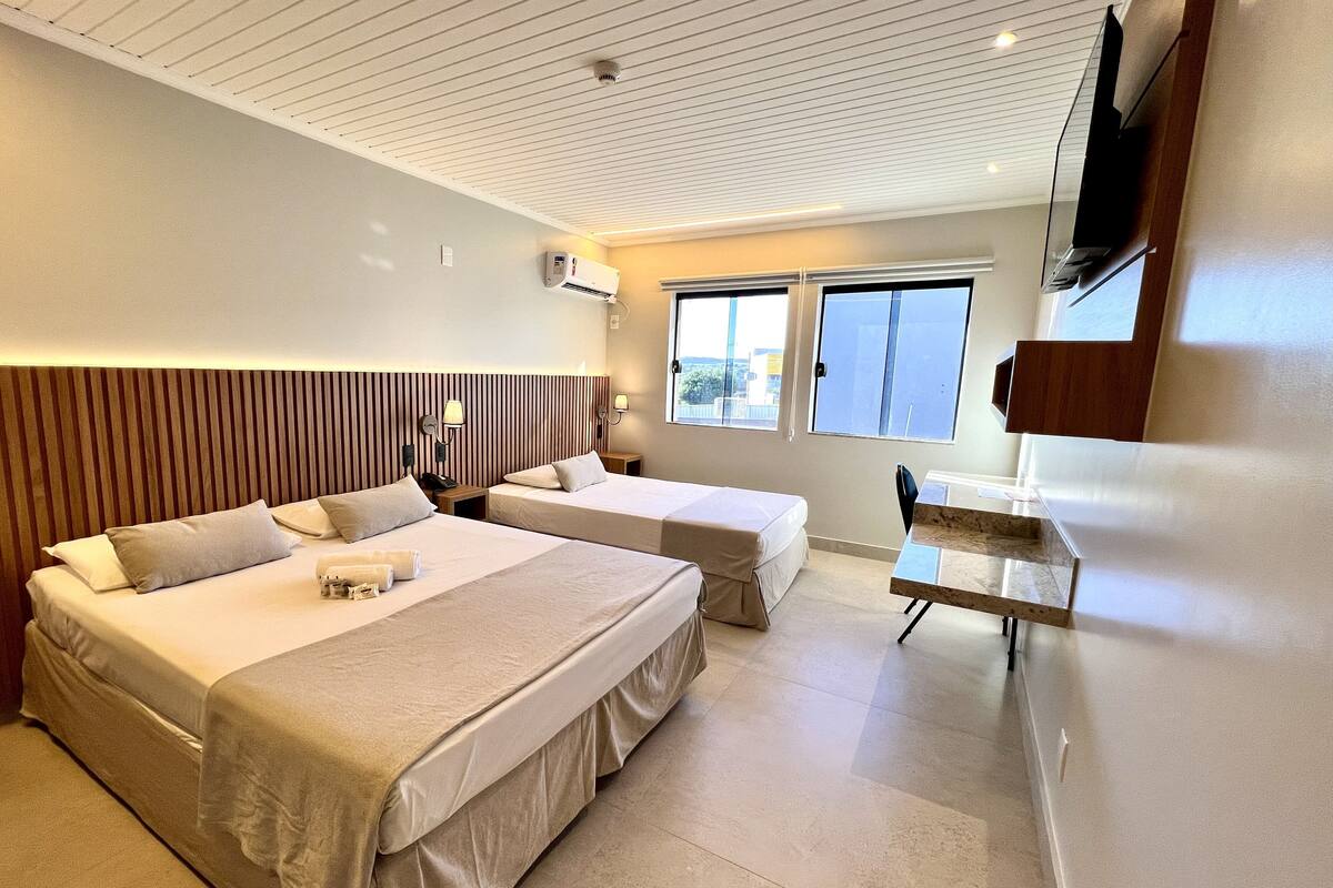 A hotel room with two beds, a desk, and a TV.