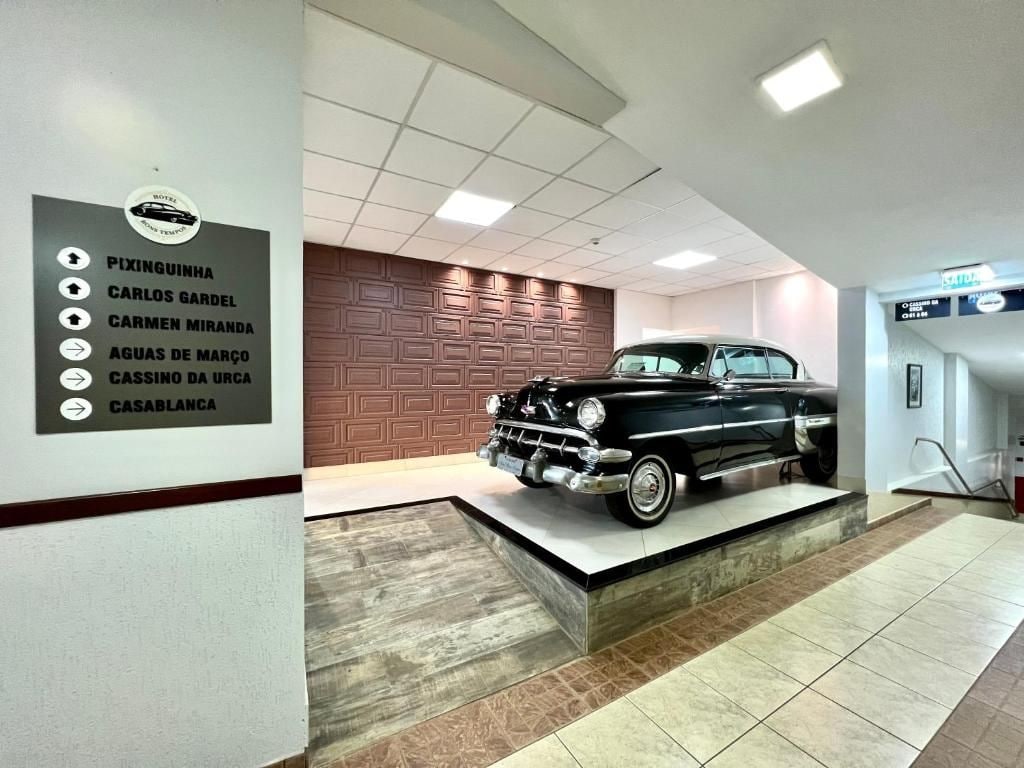A vintage car on display in a hotel lobby with a directional sign listing nearby locations.