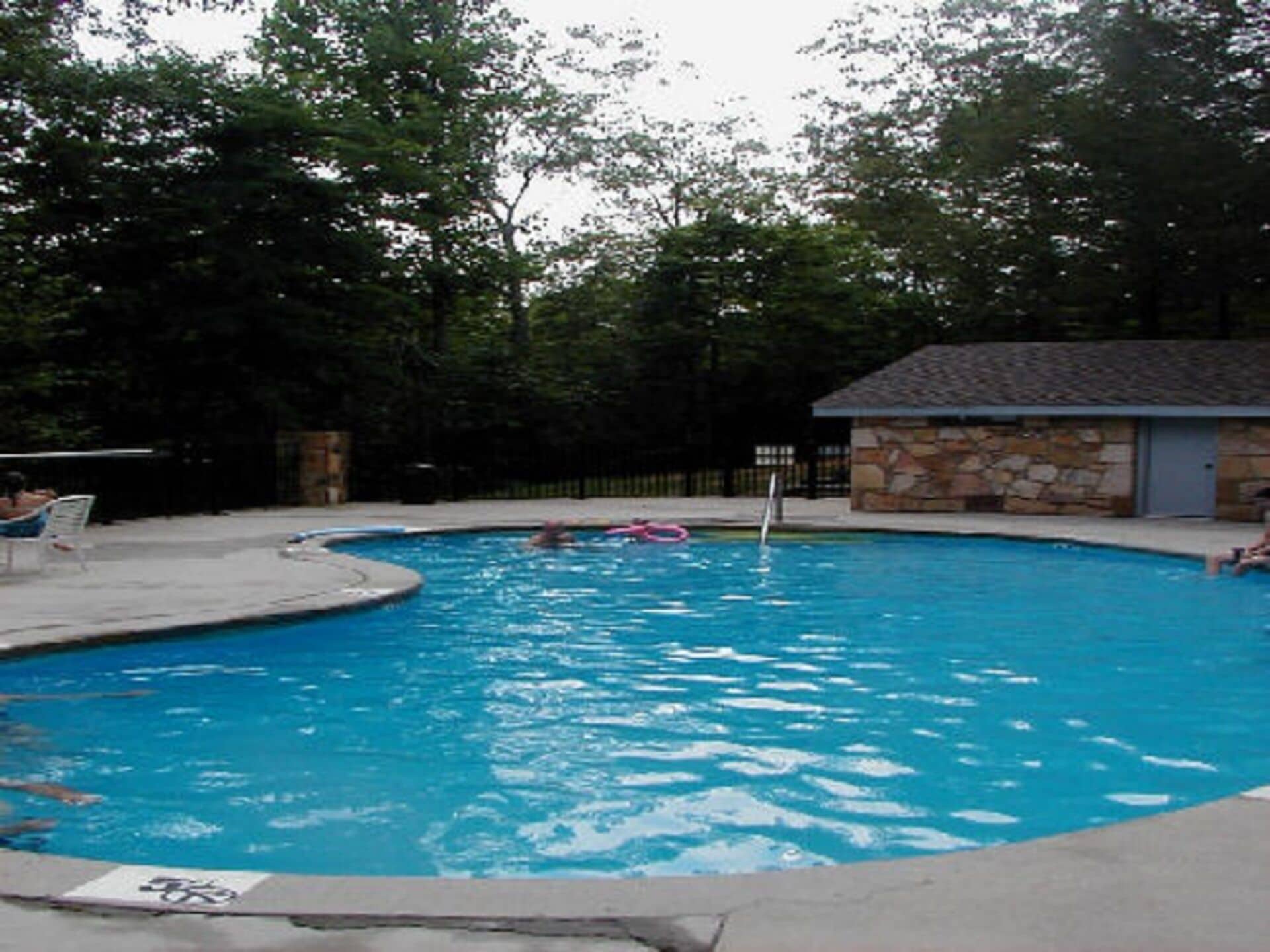 A swimming pool with a stone building and a fence in the background.