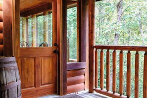 A wooden cabin entrance with a door, windows, and a wooden deck.