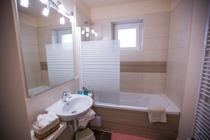 A bathroom with a sink, mirror, and bathtub.