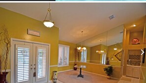 A spacious hallway with a large mirror, a chandelier, and a potted plant.