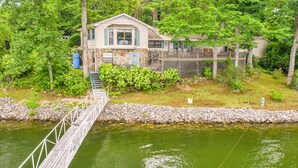Ein Haus mit einer Steinaußenwand, einer Holzterrasse und einer Brücke über dem Wasser.