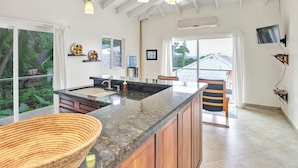 A modern kitchen with a large island, wooden cabinets, and a view of the outdoors.