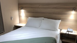 A hotel room with a bed, bedside tables, a telephone, and a wall-mounted light fixture. - The Hill Hotel and Conference Centre (Thohoyandou)
