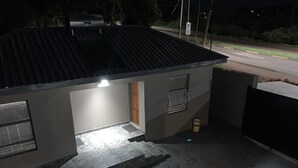 A small building with a metal roof, a door, and a window with a metal grille. - The Hill Hotel and Conference Centre (Thohoyandou)