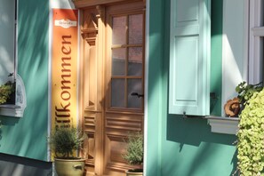 Un edificio con fachada verde, una puerta de madera y un letrero que dice "Willkommen".