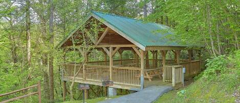 A wooden cabin with a metal roof, surrounded by trees.