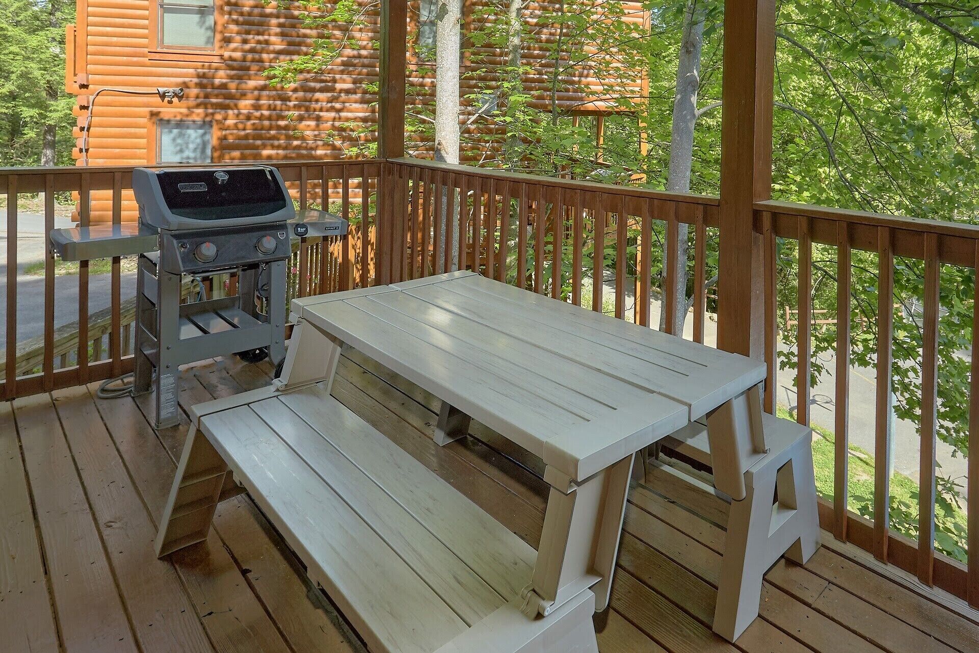 A wooden deck with a grill, a picnic table, and benches.