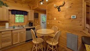 A wooden cabin interior with a kitchen, dining area, and a mounted deer head on the wall. - Cozy cabin, perfect for a honeymoon or an adventure-filled family getaway! (Gatlinburg)