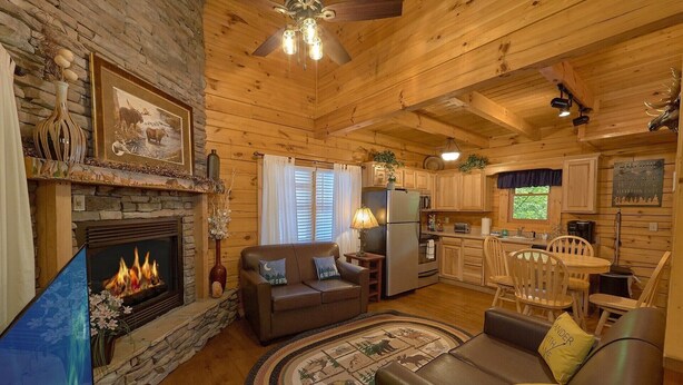 A cozy cabin interior with a fireplace, a dining area, and a kitchen. - Cozy cabin, perfect for a honeymoon or an adventure-filled family getaway! (Gatlinburg)