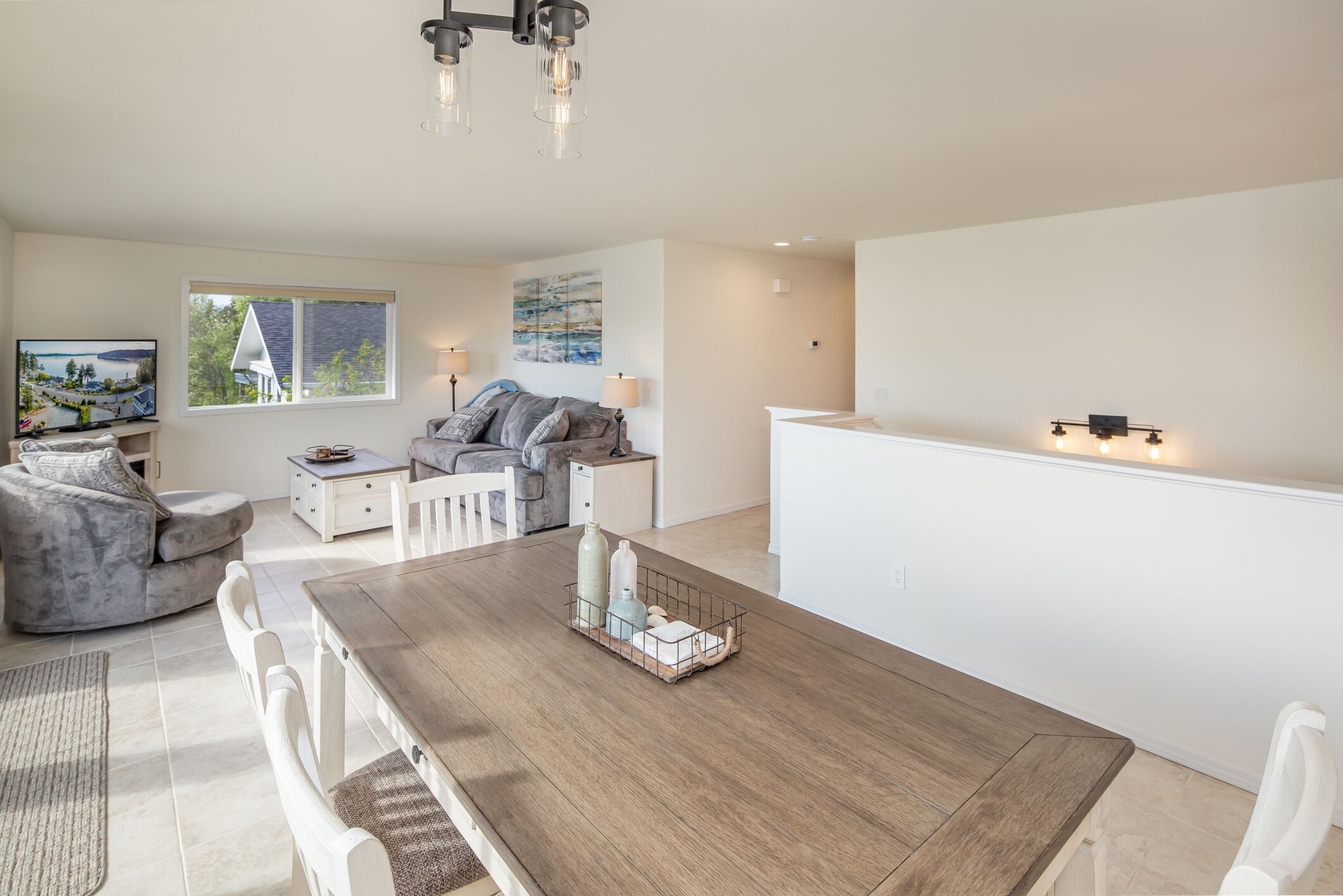 Un salon moderne avec une table à manger en bois, un canapé gris et un téléviseur posé sur un meuble.