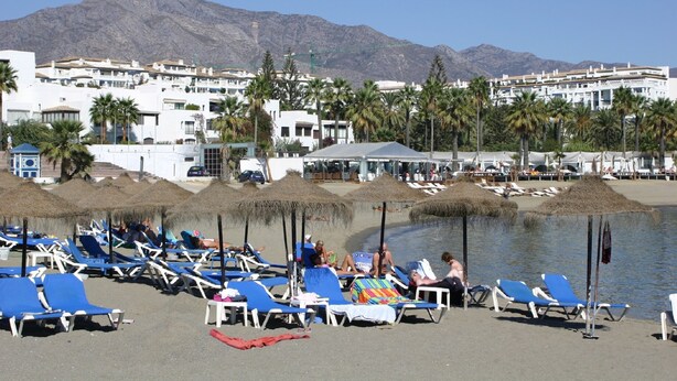 A beachside resort with sun loungers and umbrellas, a pool, and a mountain backdrop. - Beachfron Puerto Banus, 2 bed apt Playas Del Duque, Free Wifiparking 3 Pools (Marbella)
