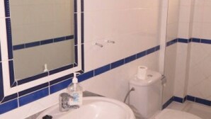 Une salle de bain avec un lavabo blanc, un miroir à cadre bleu, des toilettes et des murs recouverts de carreaux bleus.