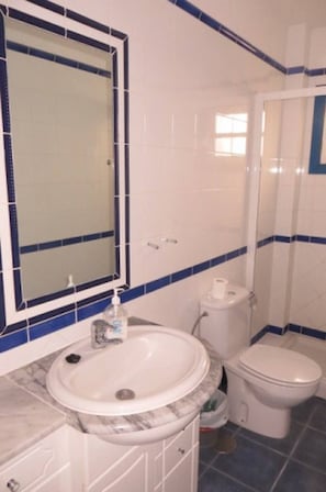 Een badkamer met een wastafel, spiegel, toilet en blauwe betegelde wanden.