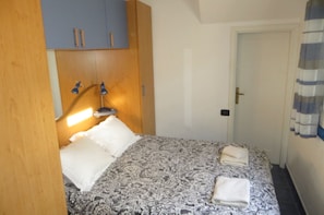 Een slaapkamer met een bed, nachtlampjes, een kledingkast en een deur.