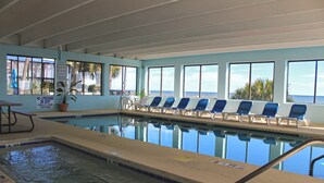 An indoor swimming pool with clear blue water, a lifeguard station, and lounge chairs facing the pool. - Holiday Sands South Resort by Palmetto Vacations (Myrtle Beach)