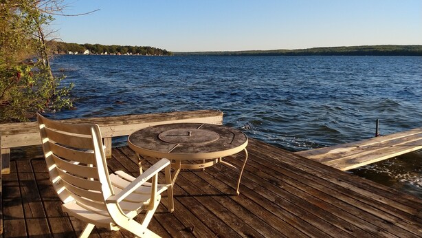 Une terrasse en bois avec une table et deux chaises, donnant sur un lac.