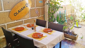 Ein Restaurant mit Backsteinwand, einem Holzschild mit der Aufschrift 'OLAJAN' und einem für vier Personen gedeckten Tisch mit Stühlen.