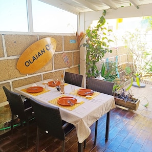 Un ristorante con un tavolo apparecchiato per quattro persone, un cartello con la scritta 'OLAJAN' e piante in vaso.