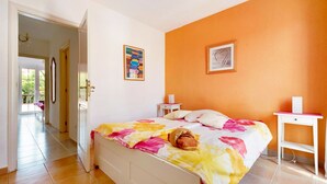 Ein Schlafzimmer mit Bett, Nachttisch, einer Tür zum Balkon.