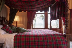 A bed with a plaid bedspread, a lamp, and curtains.