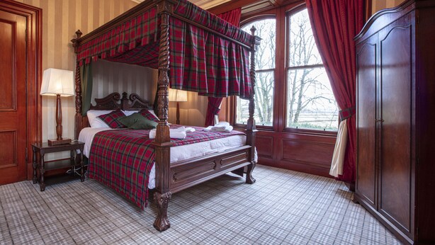 A four-poster bed with a plaid bedspread, a wooden nightstand with a lamp, and a large wardrobe. - Newton Manor House -7 Bedroom House (Cupar)