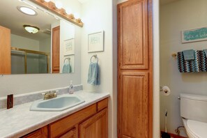 A bathroom with a sink, mirror, wooden cabinets, and a toilet. - Larkspur Trail 3 Bedroom Home by RedAwning (Bend)