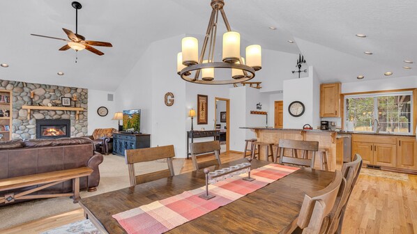 Una sala de estar amplia con chimenea, un comedor con mesa de madera y una cocina con gabinetes de madera.